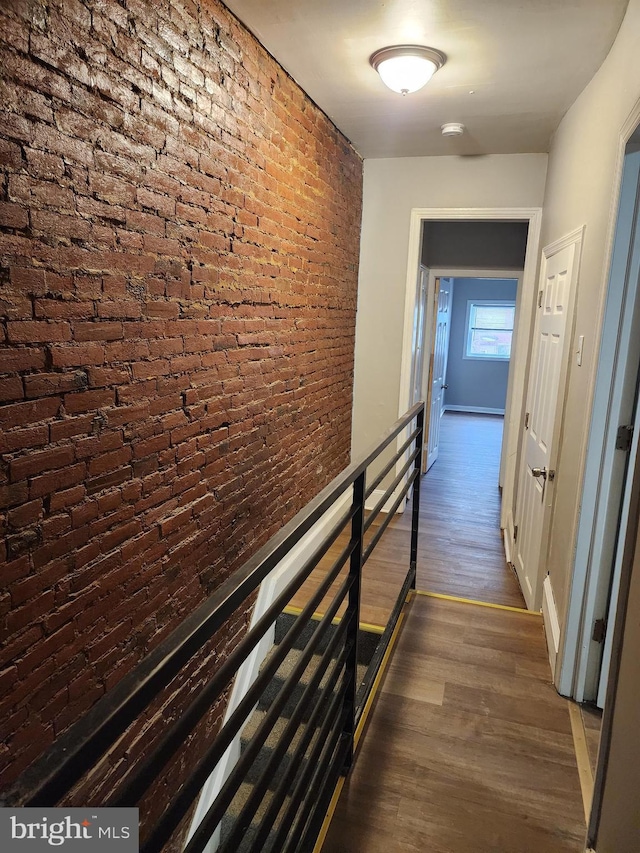 hall with brick wall and dark wood-type flooring