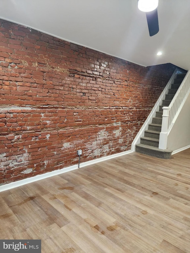 spare room featuring hardwood / wood-style flooring and brick wall