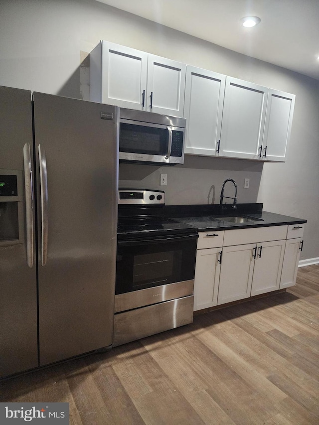 kitchen with sink, light hardwood / wood-style flooring, white cabinets, and appliances with stainless steel finishes