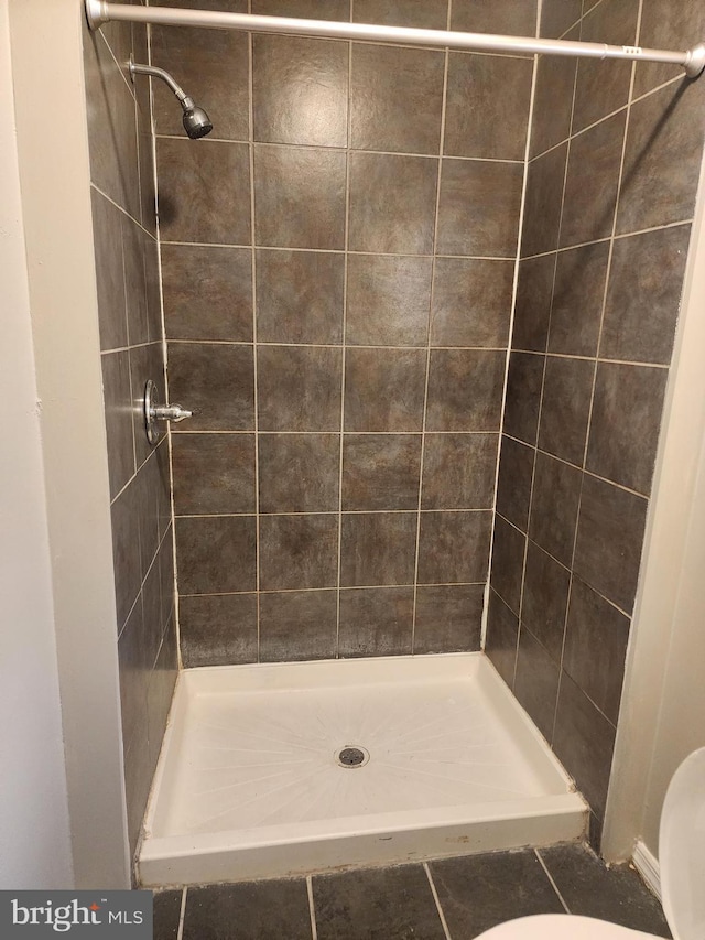 bathroom featuring tiled shower and toilet