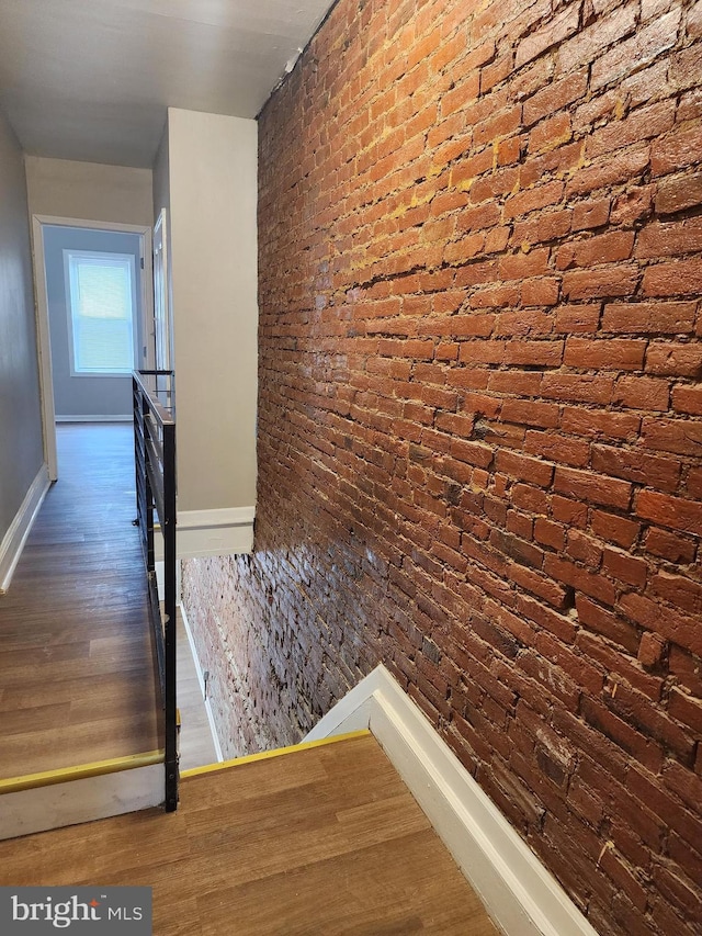 hall featuring brick wall and dark hardwood / wood-style flooring