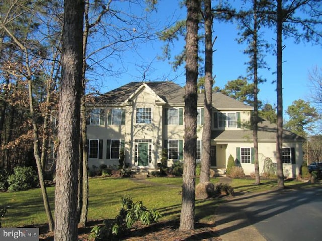 colonial inspired home featuring a front lawn