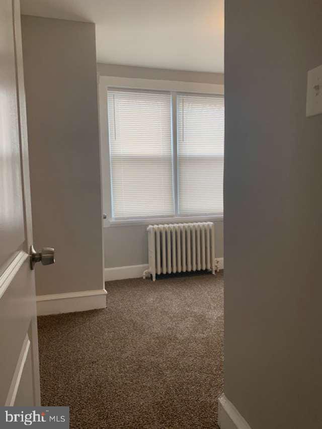 carpeted spare room featuring radiator