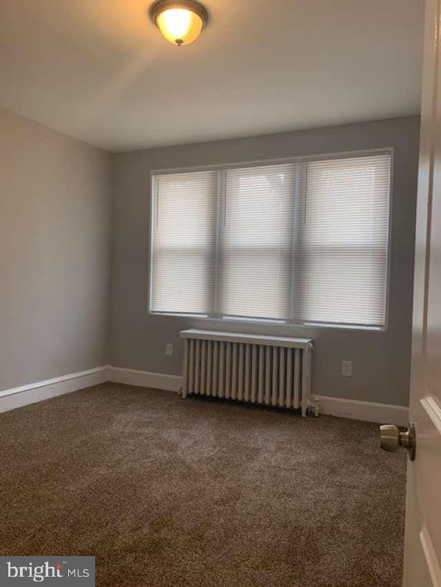 carpeted empty room with radiator