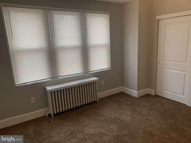 carpeted spare room featuring radiator heating unit