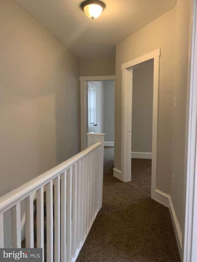 hall featuring dark colored carpet