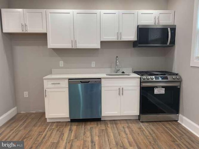 kitchen with dark hardwood / wood-style flooring, white cabinetry, sink, and appliances with stainless steel finishes