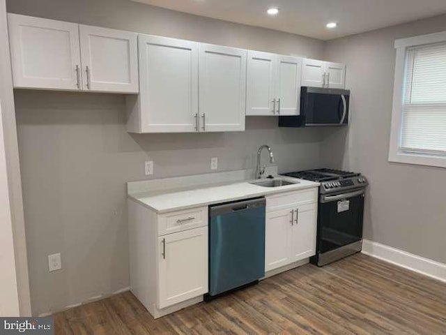 kitchen with white cabinets, dark hardwood / wood-style flooring, sink, and appliances with stainless steel finishes