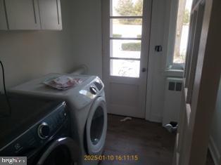 laundry area featuring cabinets, radiator heating unit, washing machine and dryer, and a wealth of natural light