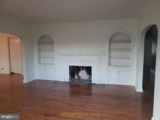 unfurnished living room with dark hardwood / wood-style floors and built in features