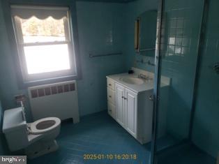 bathroom featuring vanity, radiator heating unit, and toilet