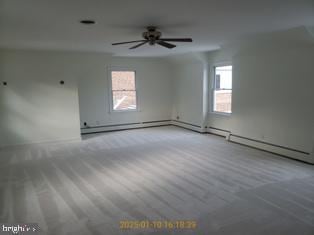 unfurnished room featuring a baseboard heating unit, ceiling fan, and carpet flooring