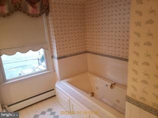 bathroom with baseboard heating and a tub to relax in