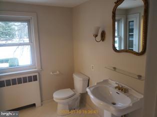 bathroom featuring sink, radiator heating unit, and toilet