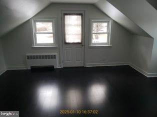 additional living space featuring lofted ceiling, radiator heating unit, and dark hardwood / wood-style floors