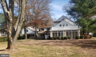 rear view of house with a yard and a sunroom