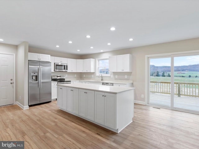 kitchen with light wood-type flooring, stainless steel appliances, white cabinetry, and sink