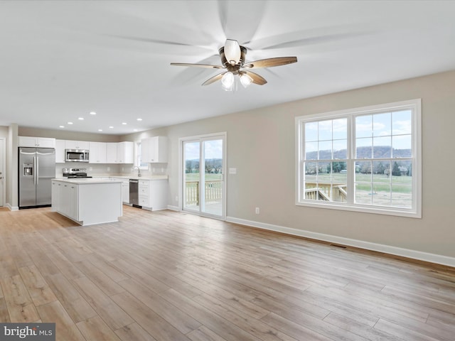 unfurnished living room with light hardwood / wood-style flooring, ceiling fan, and a healthy amount of sunlight