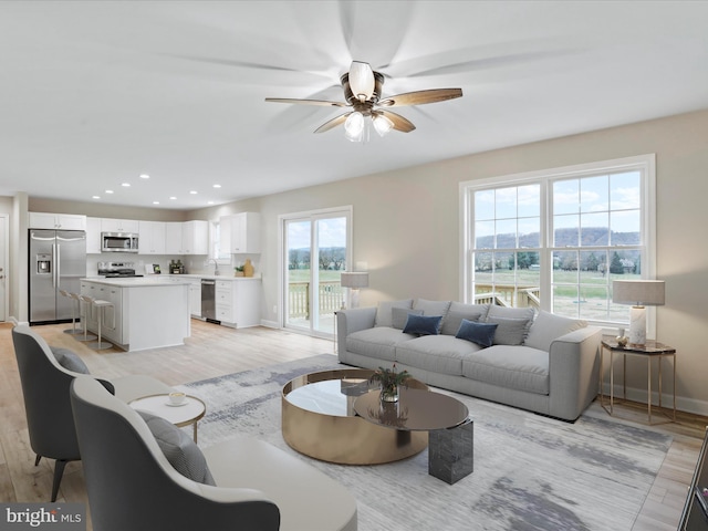 living room with ceiling fan, light hardwood / wood-style floors, and a wealth of natural light