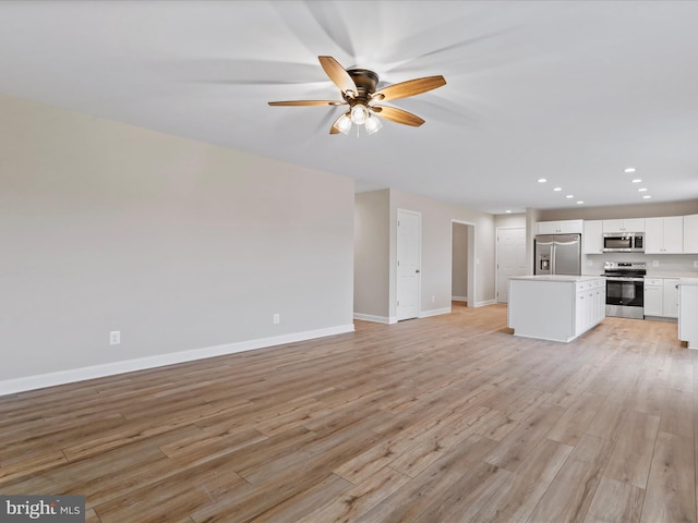 unfurnished living room featuring ceiling fan and light wood-type flooring