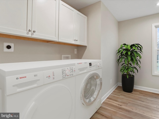 clothes washing area featuring cabinets, light wood-type flooring, and washing machine and clothes dryer