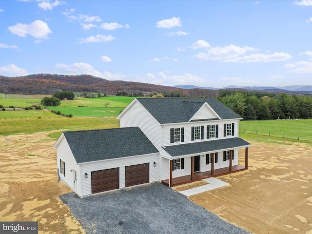 view of front of house featuring covered porch, a mountain view, a rural view, and a garage