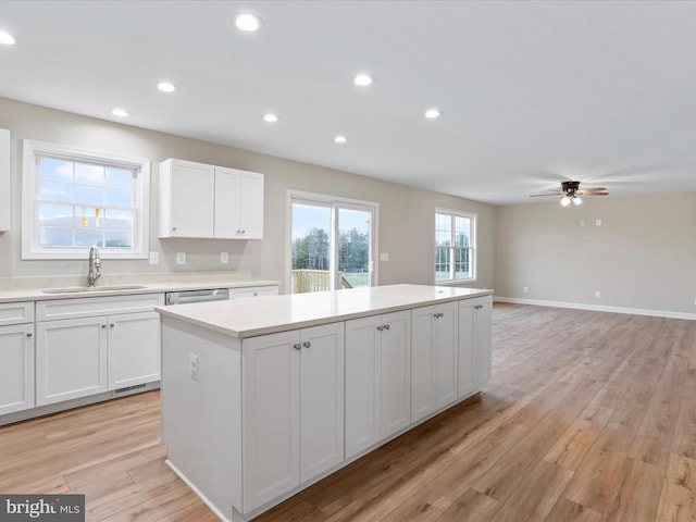 kitchen featuring ceiling fan, a center island, sink, light hardwood / wood-style floors, and white cabinets