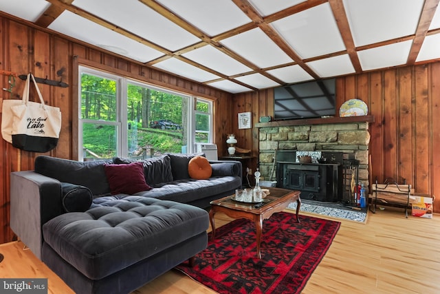 living room with a wood stove, coffered ceiling, cooling unit, wood-type flooring, and wooden walls