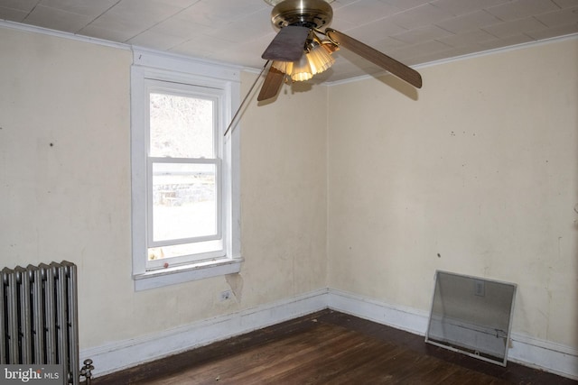 empty room with ceiling fan, crown molding, radiator heating unit, and dark wood-type flooring