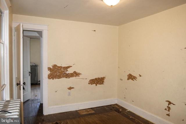 unfurnished room featuring dark hardwood / wood-style flooring and radiator heating unit