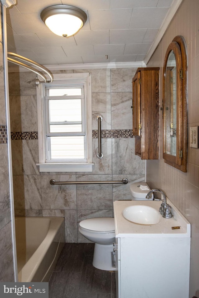 full bathroom with ornamental molding, vanity, tile walls, toilet, and tiled shower / bath