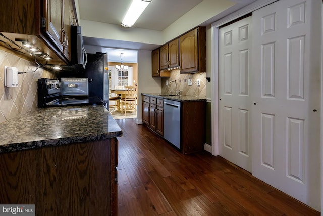 kitchen with sink, dark wood-type flooring, stainless steel appliances, backsplash, and dark stone countertops