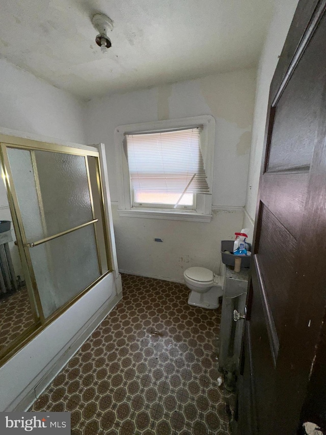 bathroom featuring bath / shower combo with glass door and toilet