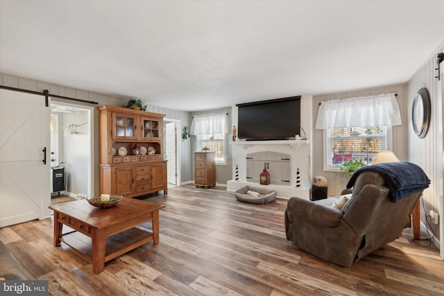 living room with a barn door, a wealth of natural light, wooden walls, and hardwood / wood-style flooring