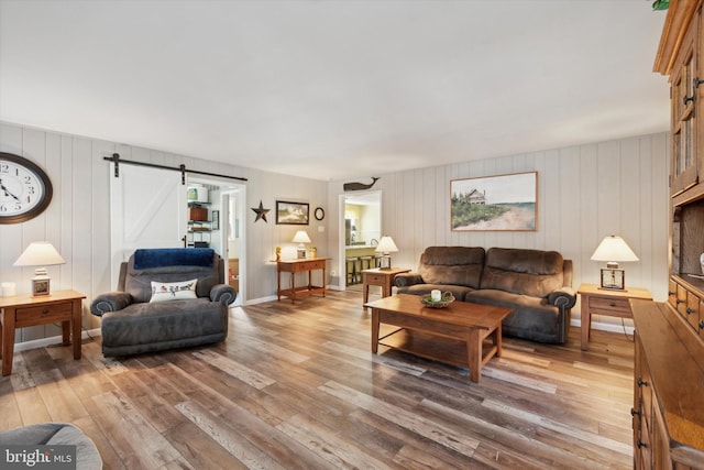 living room with hardwood / wood-style floors, a barn door, and wooden walls