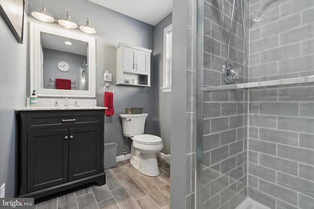 bathroom with a tile shower, vanity, and toilet