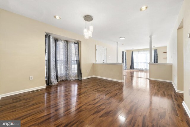 spare room with a notable chandelier and dark hardwood / wood-style floors