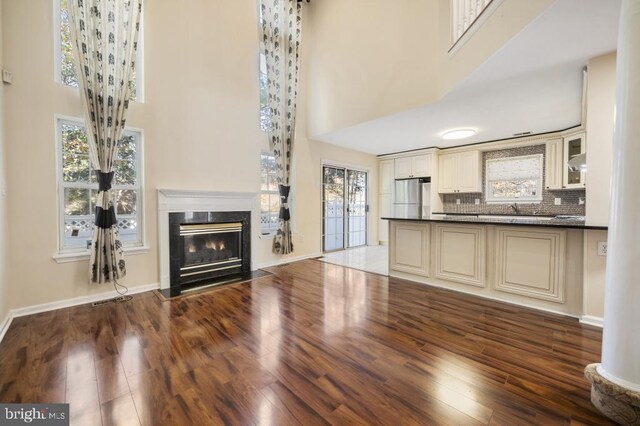 unfurnished living room featuring sink, dark wood-type flooring, and a high ceiling