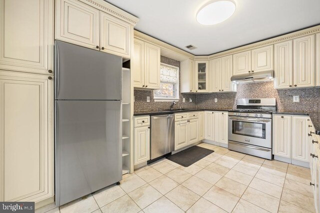 kitchen featuring decorative backsplash, appliances with stainless steel finishes, light tile patterned floors, and cream cabinets