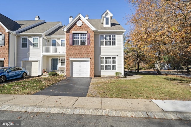 view of property featuring a balcony, a front lawn, and a garage