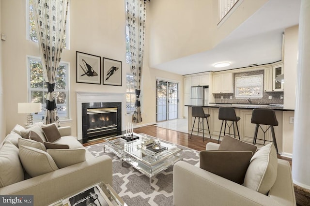 living room with sink, a towering ceiling, and light hardwood / wood-style floors