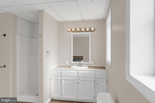 bathroom with a shower, a drop ceiling, and vanity