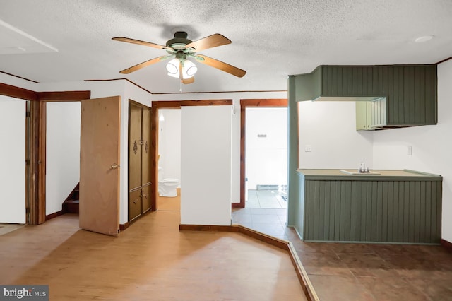 kitchen with ceiling fan, green cabinets, a textured ceiling, and light hardwood / wood-style flooring