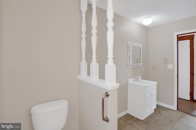 bathroom featuring tile patterned flooring, vanity, toilet, and a textured ceiling