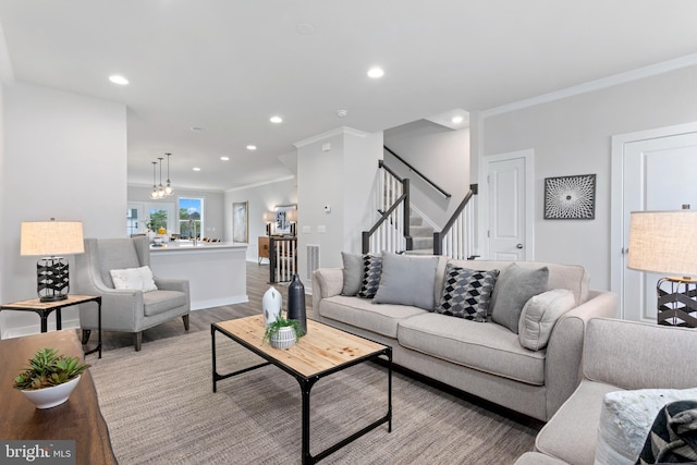 living room featuring a chandelier, light hardwood / wood-style flooring, and ornamental molding