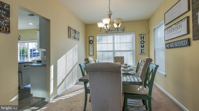 carpeted dining area featuring a wealth of natural light and a chandelier