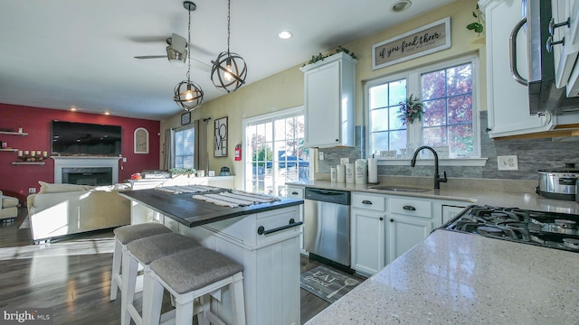 kitchen featuring dark hardwood / wood-style flooring, stainless steel dishwasher, sink, decorative light fixtures, and white cabinets