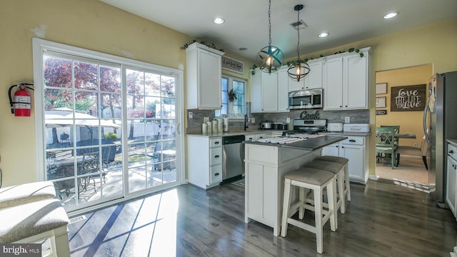 kitchen with white cabinetry, a center island, decorative light fixtures, and appliances with stainless steel finishes