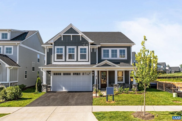 craftsman-style house featuring covered porch, a front yard, and a garage