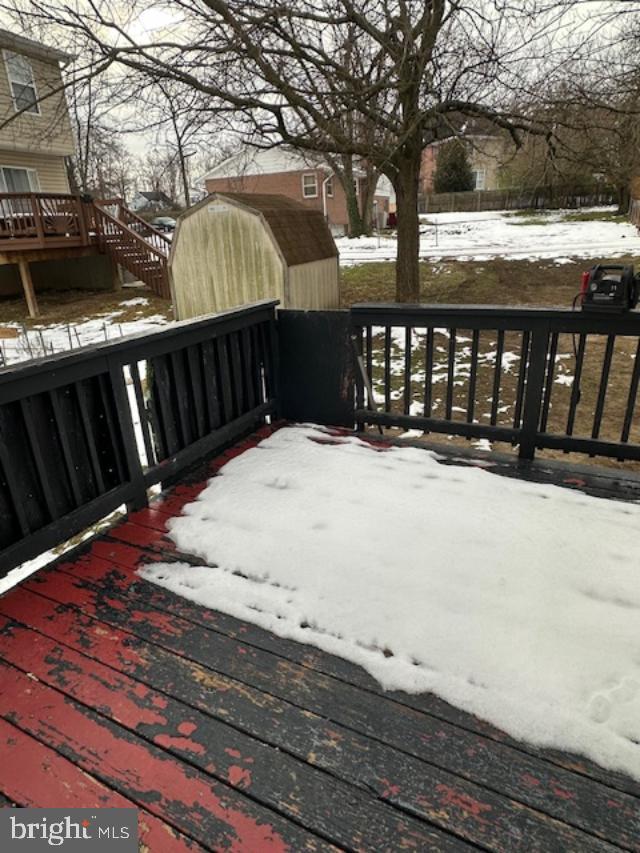 snow covered deck featuring a shed